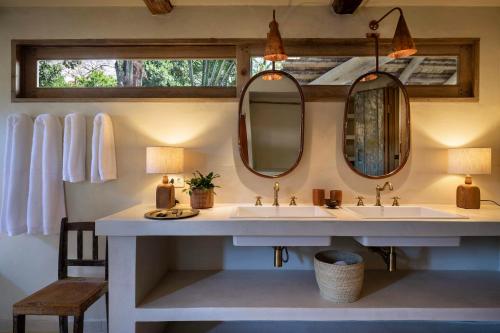 a bathroom with two sinks and two mirrors at Na Praça Hotel in Trancoso