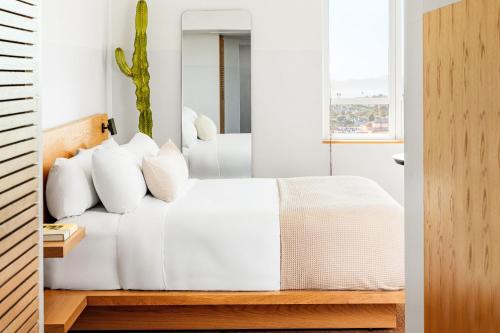 a bedroom with a white bed with white pillows at Hotel June West LA, a Member of Design Hotels in Los Angeles