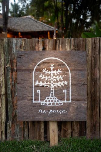 a sign on a wooden fence with a tree on it at Na Praça Hotel in Trancoso