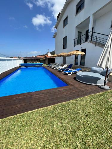a swimming pool with chairs and umbrellas next to a building at Casa do Titó in Lanhelas