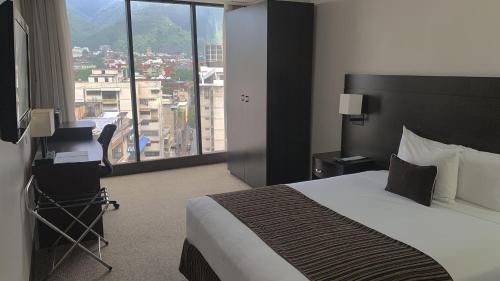 a hotel room with a bed and a large window at HOTEL CHACAO SUITES in Caracas