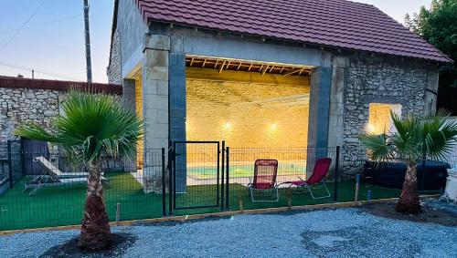 una valla con dos palmeras frente a un edificio en maison chaleureuse ,avec piscine, spa, Futuroscope, en Jaunay-Clan