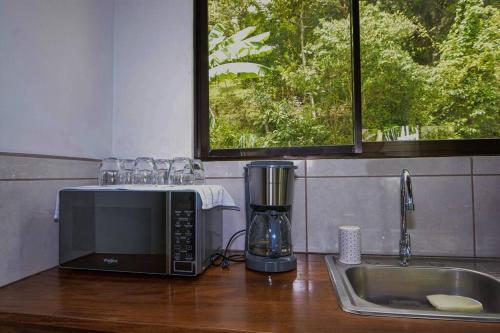 a kitchen counter with a microwave and a sink at Casa Curré Monteverde in Monteverde Costa Rica