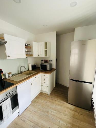 a kitchen with white cabinets and a stainless steel refrigerator at FILMAP- charmante Kreuzgewölbe-Whg im Herzen der Altstadt-Ideal für Paare & Geschäftsreisende in Görlitz