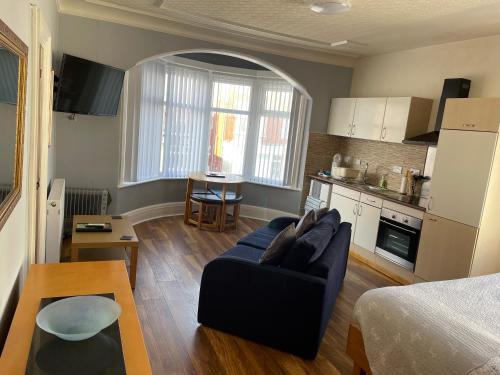 a living room with a blue couch and a kitchen at San Remo Apartments in Blackpool