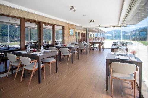 a dining room with tables and chairs and windows at Quinta de Cabanas Douro Country House in Penha Longa