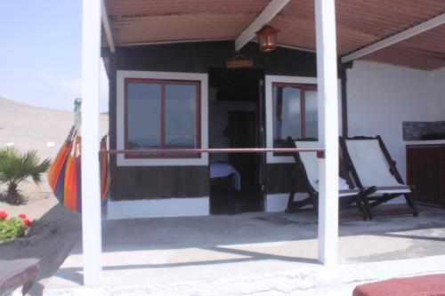 un porche de una casa de playa con mecedora en Hotel Las Aldas, en Casma
