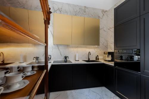 a kitchen with black cabinets and white counter tops at Premium apartment in Parisian style in the heart of Old Krakow in Krakow