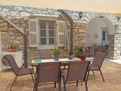 un patio con mesa, sillas y pared de piedra. en Smaragdas Paradise, en Hydra