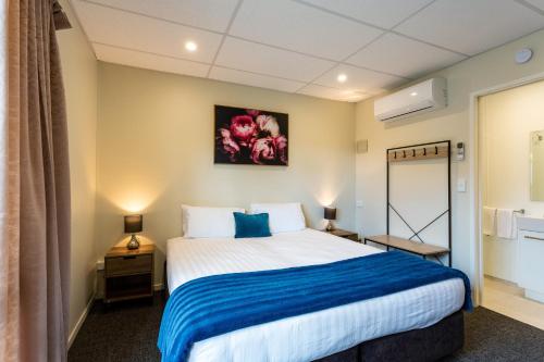 una camera da letto con un grande letto con una coperta blu di Mercer Motel a Mercer