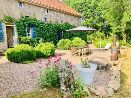 un jardín con mesa, sombrilla y flores en Ruime woning in de Morvan, Bourgogne met seizoensgebonden zwembad, en Brassy