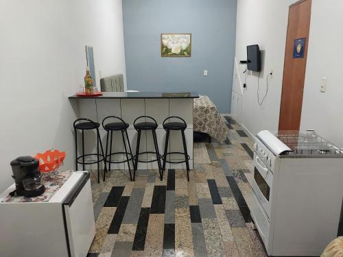 a kitchen with a counter and stools in a room at Kitnet da Sidi in São Thomé das Letras