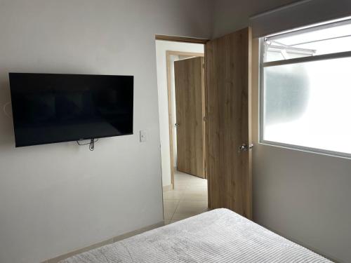 a bedroom with a flat screen tv on the wall at Apto familiar con vista a la ciudad in Envigado