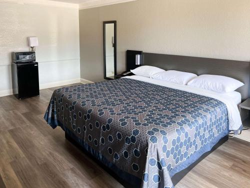 a bedroom with a large bed with a blue comforter at Motel 6-Monroe, LA in Monroe