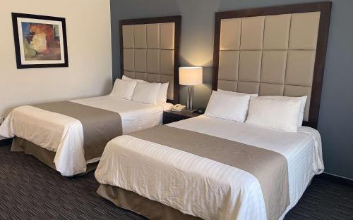 a hotel room with two beds and a lamp at Best Western Plus Chihuahua Juventud in Chihuahua