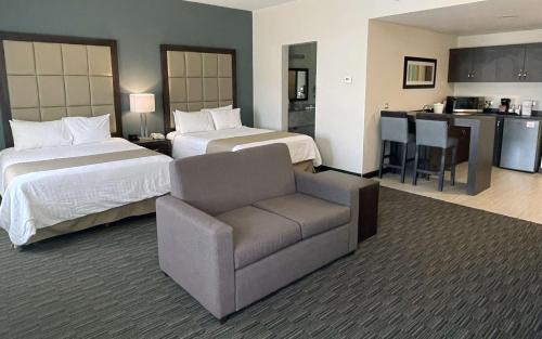 a hotel room with two beds and a chair and a kitchen at Best Western Plus Chihuahua Juventud in Chihuahua