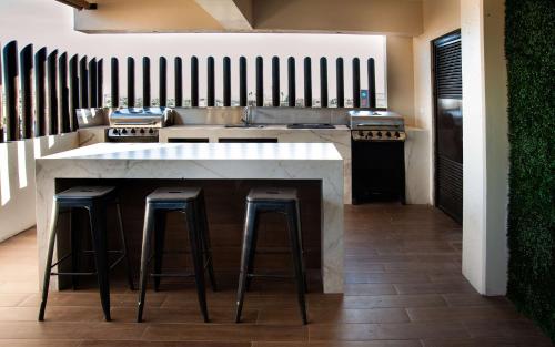 a kitchen with a counter with stools and a sink at Best Western Plus Chihuahua Juventud in Chihuahua