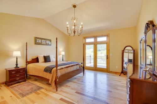 a bedroom with a bed and a chandelier at Hot Tub and Golf Course Views Luxe Sturgis Home! in Sturgis