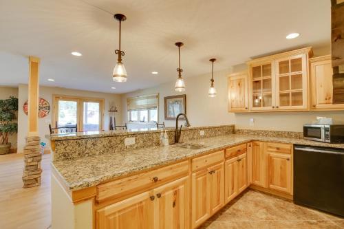 a kitchen with wooden cabinets and granite counter tops at Hot Tub and Golf Course Views Luxe Sturgis Home! in Sturgis