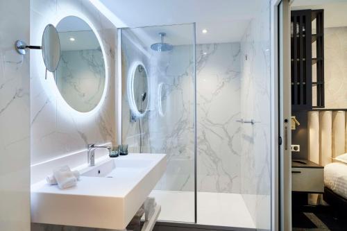 La salle de bains blanche est pourvue d'un lavabo et d'une douche. dans l'établissement Best Western Premier Hotel des Vignes et des Anges, à Pauillac