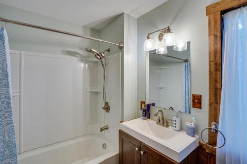 a bathroom with a sink and a tub and a mirror at Lakefront West Sand Lake Home with Beach Access! 