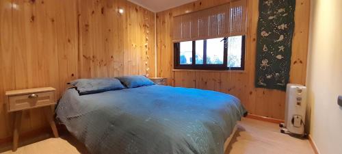 a bedroom with a blue bed and a window at Casa con linda vista de montaña y tinaja in Curacaví
