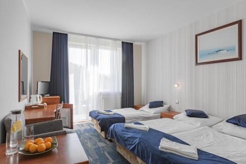 コウォブジェクにあるPensjonat KoGaのベッド3台とテーブルが備わるホテルルームです。