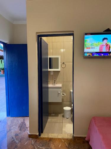 a bathroom with a toilet and a tv on a wall at Cantinho caipira in Aparecida