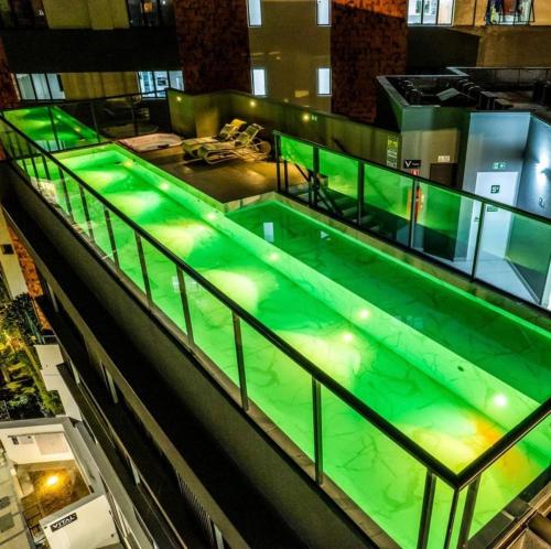 una piscina cubierta con iluminación verde en un edificio en Apartamentos Centro Poços de Caldas, en Poços de Caldas