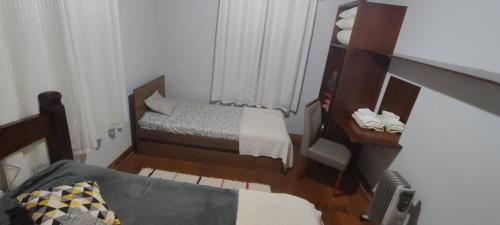 a small room with two beds and a table at Recanto Dorinha in Campos do Jordão