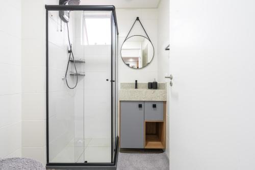 ein Badezimmer mit Dusche mit Spiegel und Waschbecken in der Unterkunft Apartamento 150m da PRAIA com SACADA, WI-FI AR CONDICIONADO, PISCINA, PORTARIA 24h, PLAYGROUND e vaga de GARAGEM in Piçarras