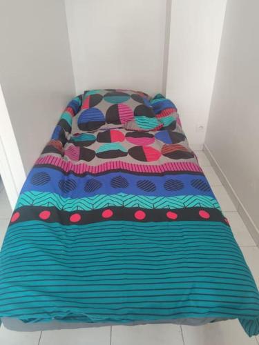 a bed with a colorful blanket on top of it at Séjour chaleureux in Aubervilliers