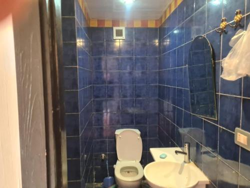 a blue tiled bathroom with a toilet and a sink at Porto marina in El Alamein
