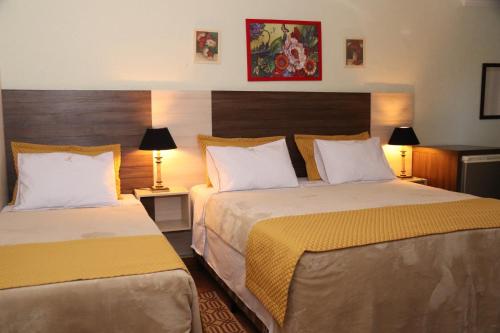 a hotel room with two beds and two lamps at HOTEL ESTÂNCIA - ESTACIONAMENTO GRATUITO ROTATIVO - Vagas Limitadas in Poços de Caldas