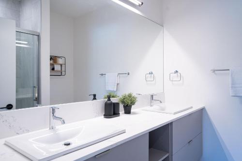a white bathroom with two sinks and a mirror at North Bowl Nook by Revelstoke Vacations in Revelstoke