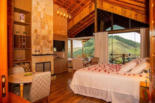 a bedroom with a bed and a table and a fireplace at Chalés Alto dos Pires in São Bento do Sapucaí