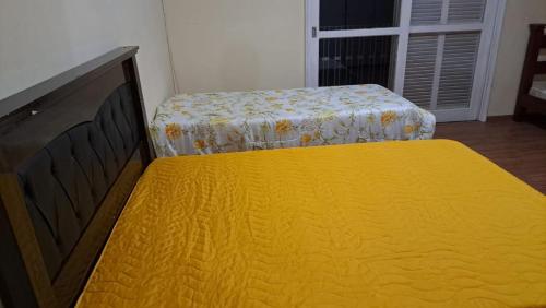 two beds in a room with a yellow mattress at hospedagens regina in Águas de Lindóia