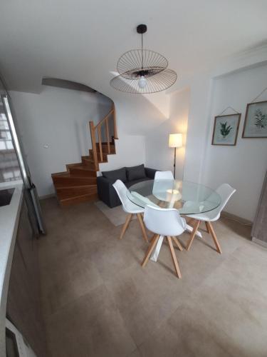 a living room with a glass table and white chairs at TORREÃO HOUSE in Guarda