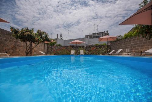 a swimming pool with blue water and umbrellas at B&B Don Alessandro in Surbo