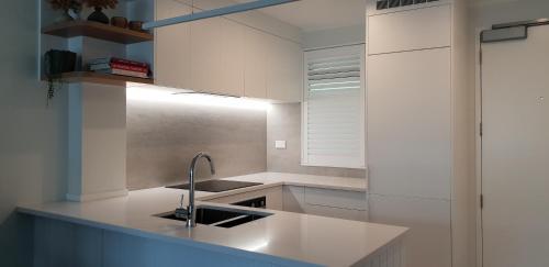 a kitchen with white cabinets and a sink at The Atrium in Mount Maunganui