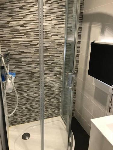 une douche avec une porte vitrée dans une salle de bain dans l'établissement Maison de village, à Laurens