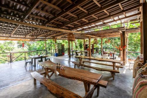 a pavilion with wooden tables and benches in a forest at Colores de la Sierra in Minca