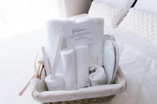a basket filled with white items on a bed at The Onyx at One Regis Upper Penthouse flat in Bacolod