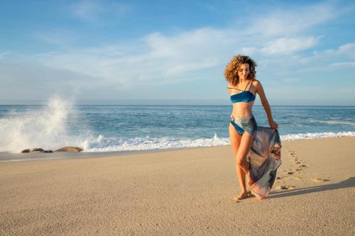 a woman in a bikini walking on the beach at Paradisus Los Cabos - Adults Only - All Inclusive in Cabo San Lucas