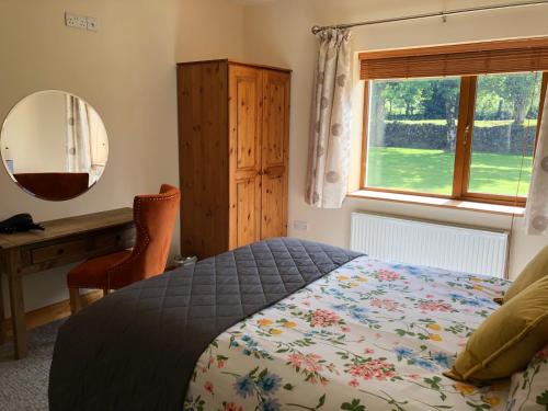 1 dormitorio con cama, escritorio y ventana en Lissyclearig Lodge en Kenmare