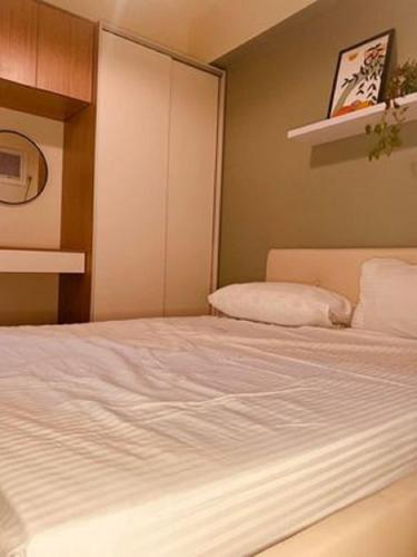 ein Schlafzimmer mit einem großen weißen Bett in einem Zimmer in der Unterkunft Spacious 2BR near Uptown BGC in Manila