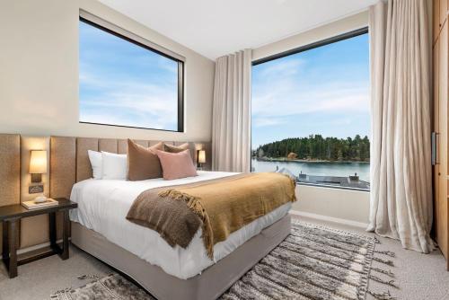 een slaapkamer met een bed en een groot raam bij Lakeside Terrace Luxury by Relaxaway Holiday Homes in Queenstown