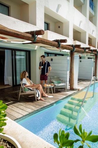 a man and woman sitting in chairs next to a swimming pool at Paradisus Los Cabos - Adults Only - All Inclusive in Cabo San Lucas
