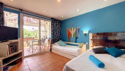1 dormitorio con 2 camas, TV y balcón en Appartement Varangue, Anse des rochers, en Saint-François