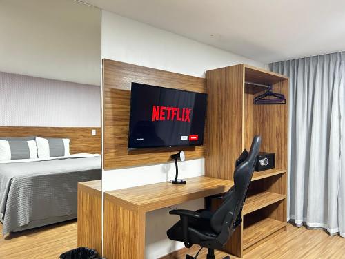 a bedroom with a bed and a desk with a television at Belavista Hotel in Itaberaba